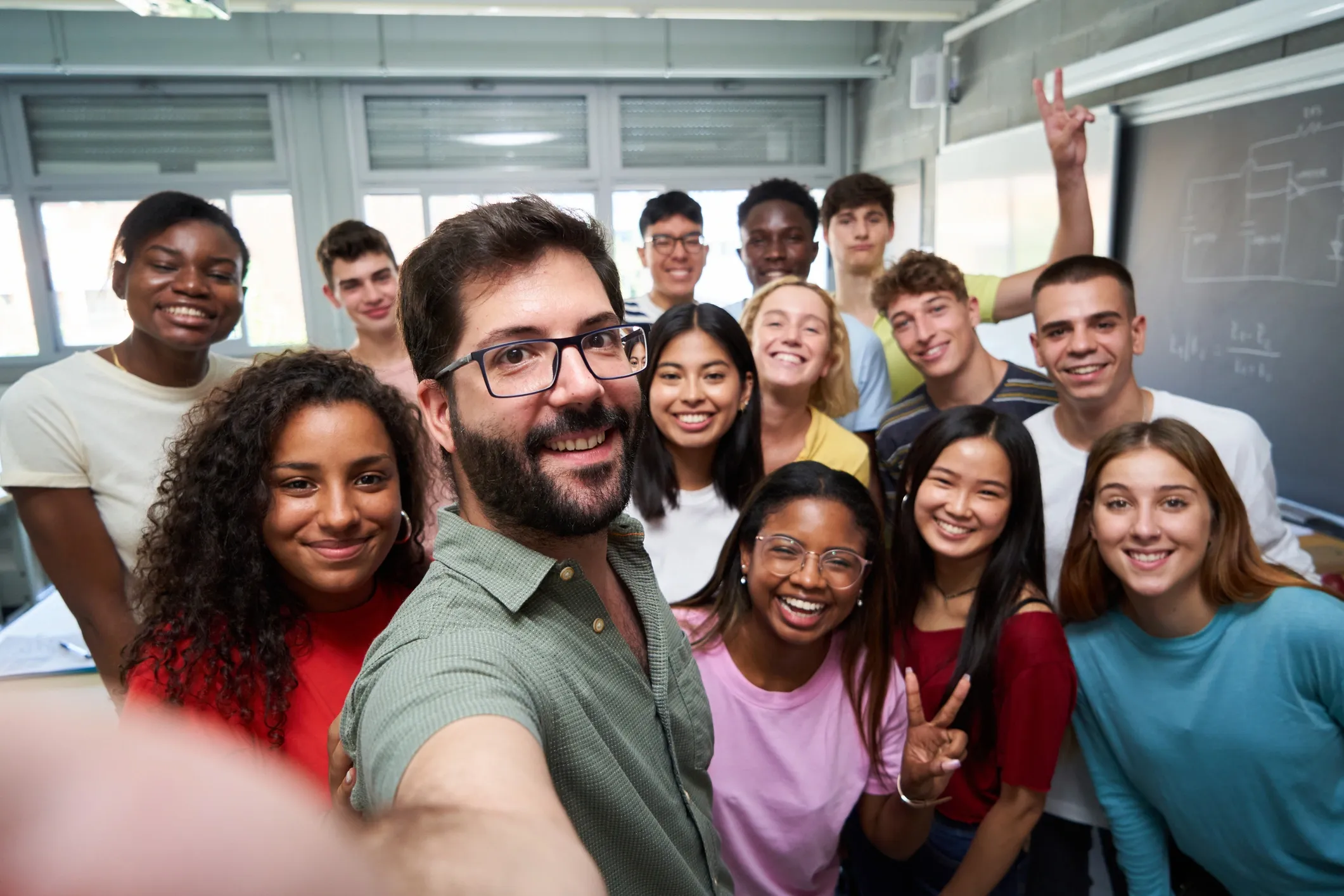 teacher taking selfie with smiling students behind him